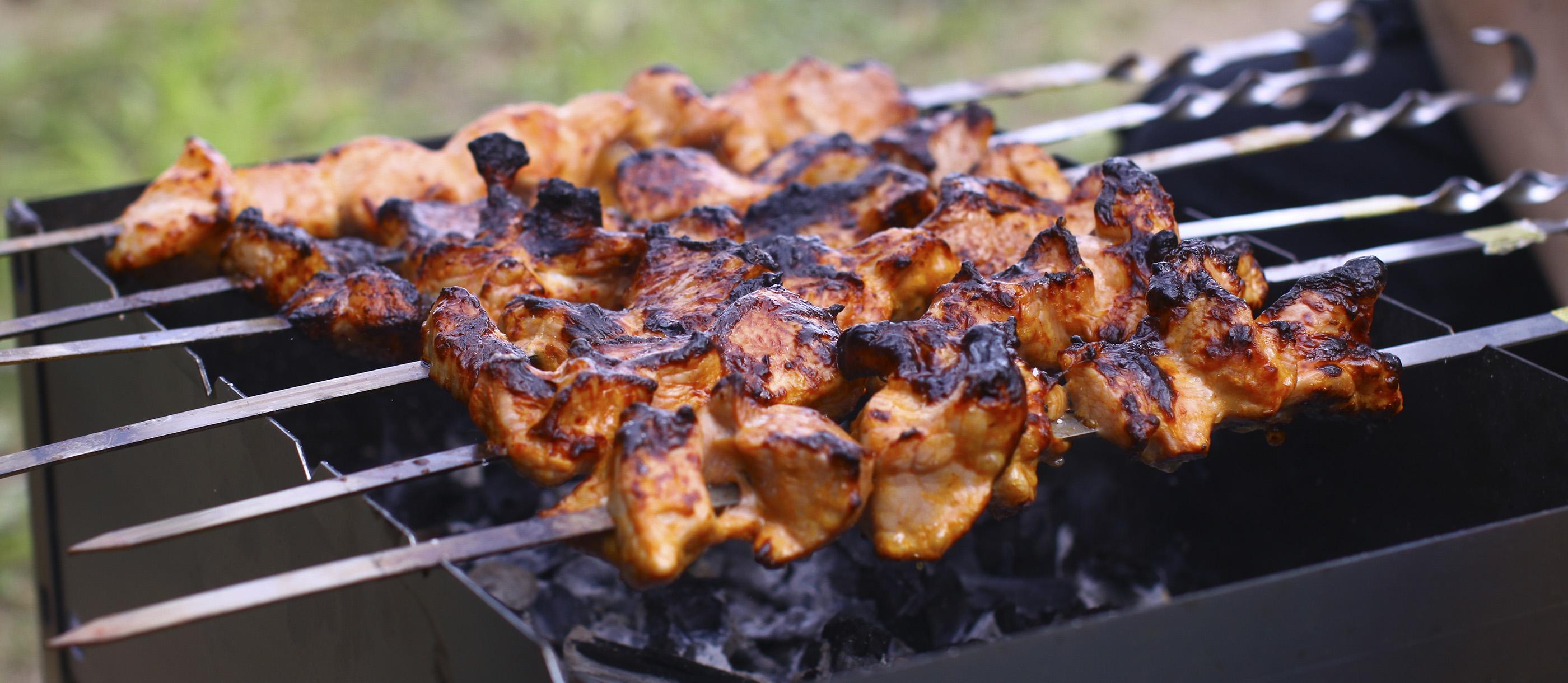 Grilling marinated shashlik preparing on a barbecue grill over charcoal.  Shashlik is a form of Shish kebab popular in Eastern Europe. Shashlyk (meaning  skewered meat) was originally made of lamb. Stock Photo